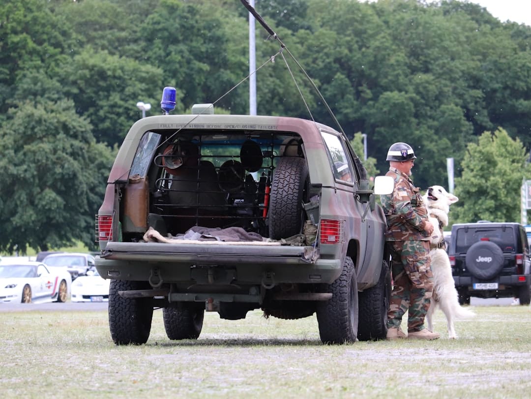 VA disability rating — Soldier with a white dog next to a camouflage suv.