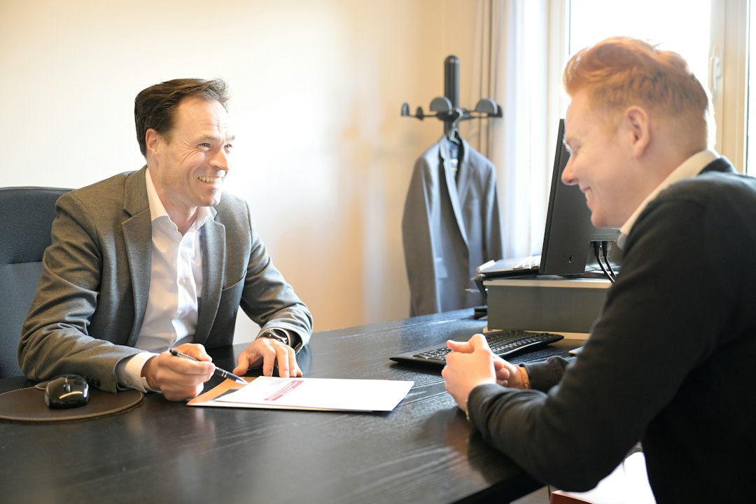 veteran service dog — Two smiling men discussing documents at an office desk